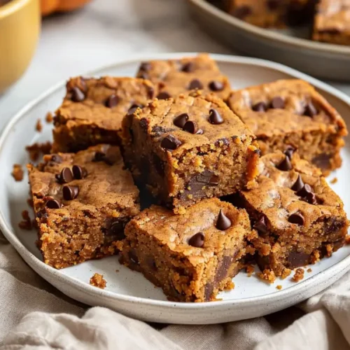 Close-up slices of Gluten-Free Dairy-Free Pumpkin Blondies with soft orange crumb and melted chips.
